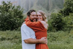 A joyful embrace follows a successful proposal with misty mountains in the background.