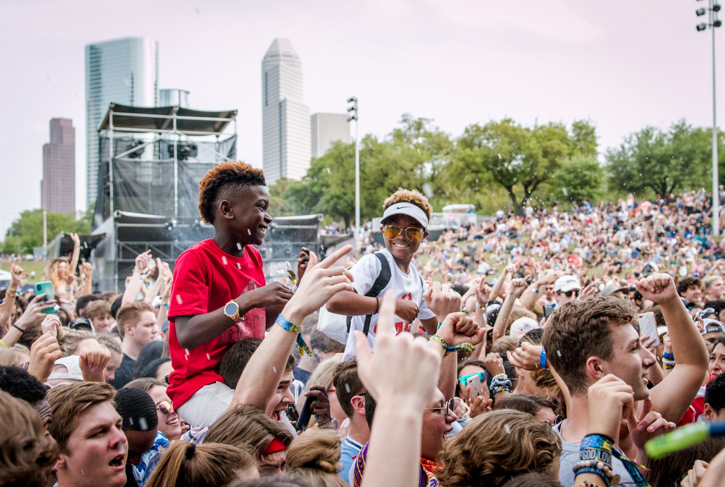 Crowded outdoor music festival with performers on stage and enthusiastic audience.