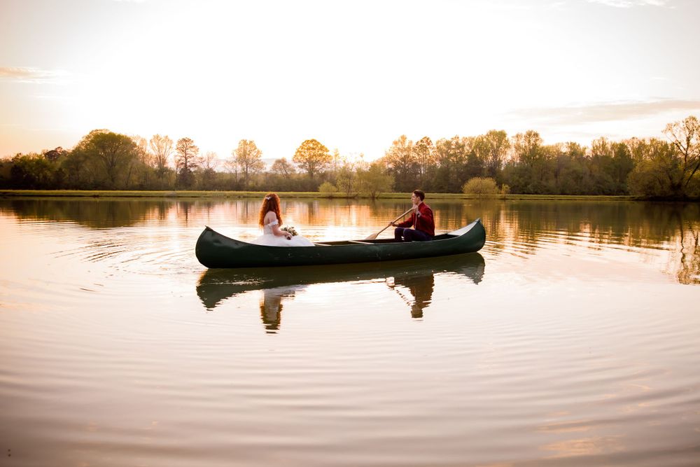 Couple rides in canoe on calm lake during sunset.