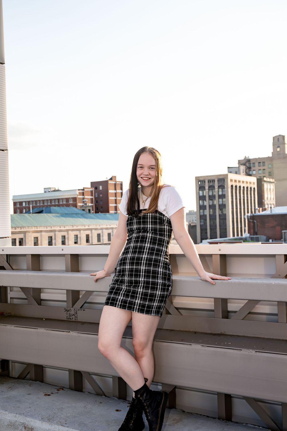 City rooftop fashion shoot featuring plaid overall dress and white t-shirt combo.