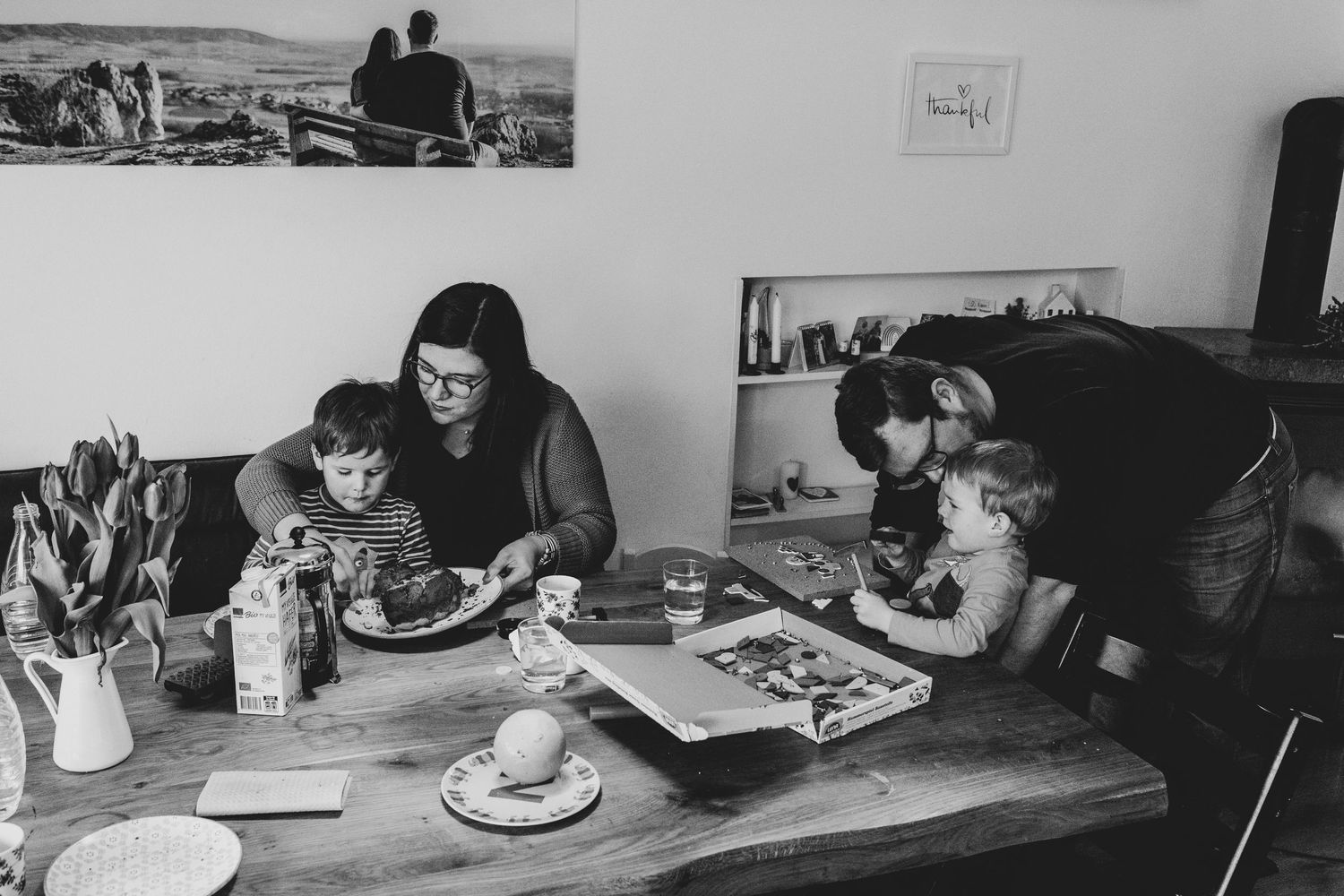 Familie mit 3 jährigen Zwillingen am Esstisch, jedes Elternteil kümmert sich um ein Kind