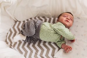 Baby liegt im Stubenwagen und überstreckt sich