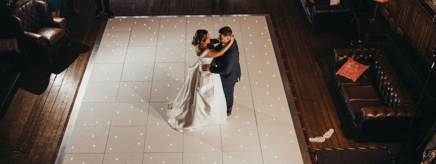 Aerial view of a couple dancing on an illuminated dance floor.