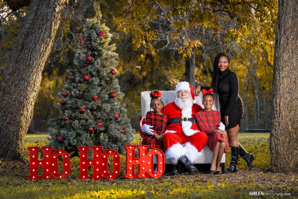 Christmas photo setup with decorated evergreen and red gift boxes in autumn setting.
