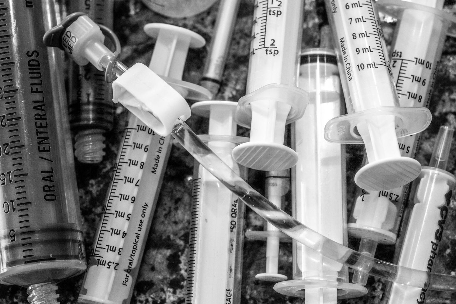 Black and white close-up of medical syringes with measurement markings.