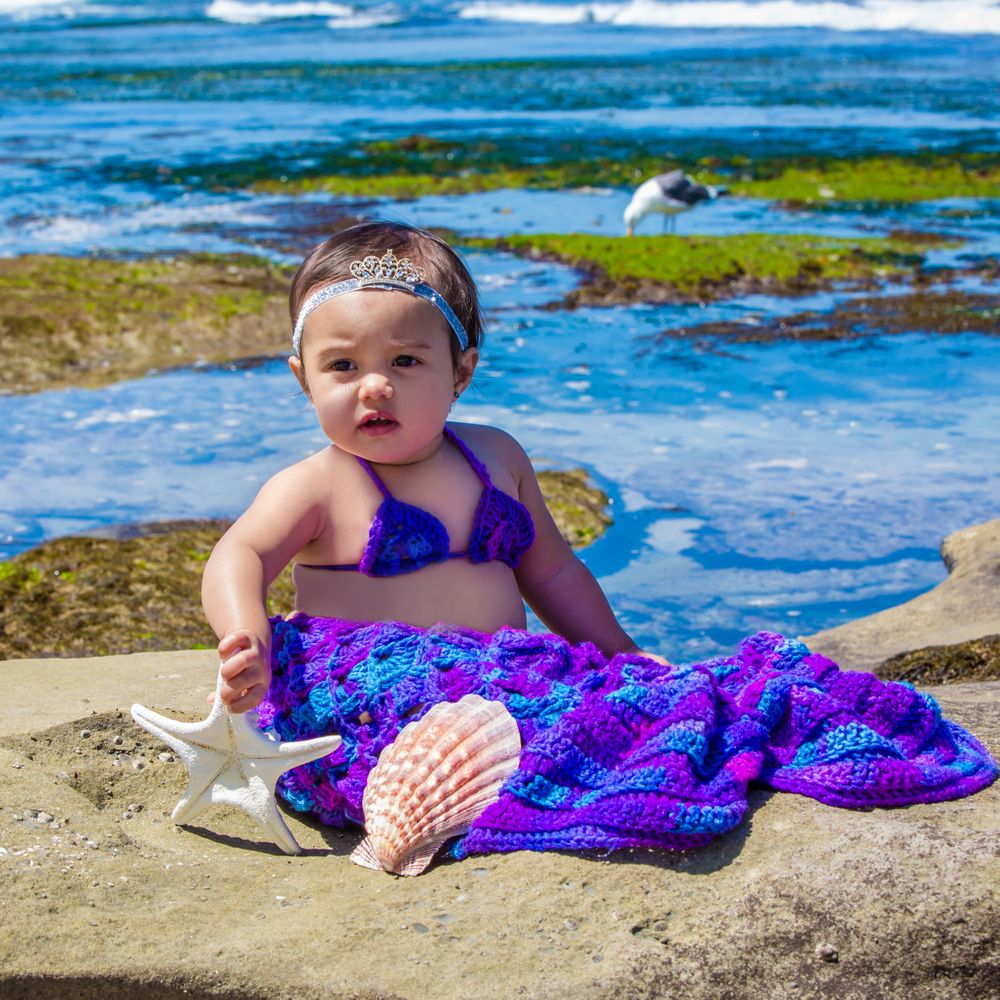Beach photography series showing purple mermaid costume and seashells against ocean backdrop.