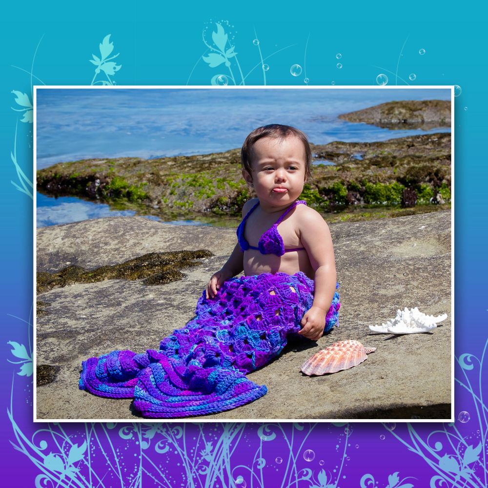A vibrant purple mermaid tail costume photographed against a rocky coastal backdrop.