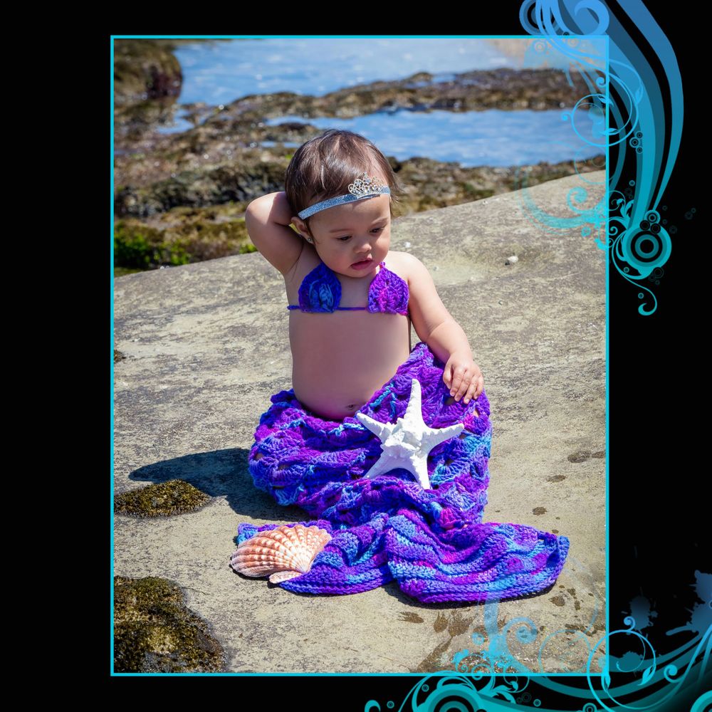 A beachside photo with a starfish and shimmering purple mermaid tail costume.