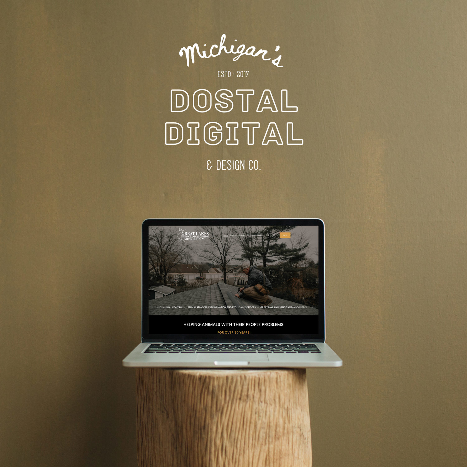 A laptop displaying 'Michigan's Dostal Digital' on a wooden pedestal against a tan background.
