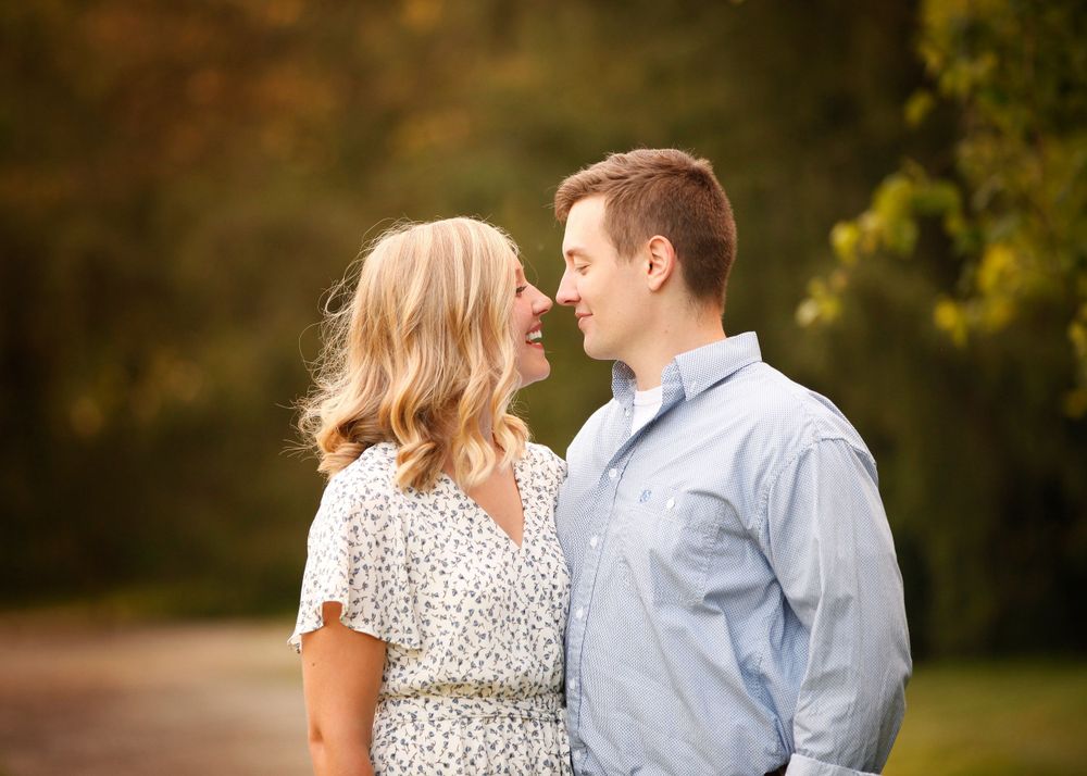 A couple in casual attire sharing an intimate moment in a sunlit outdoor setting.