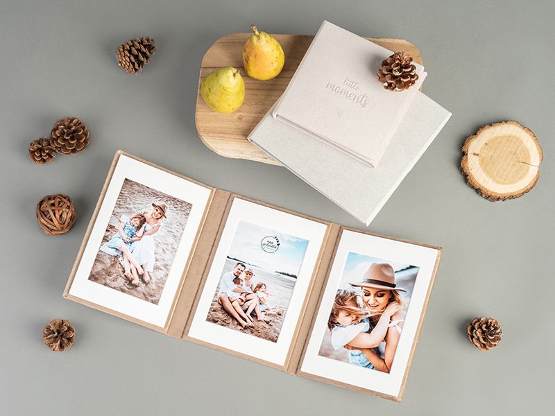 Triple photo frame display with pinecones and seasonal decorations on grey background.