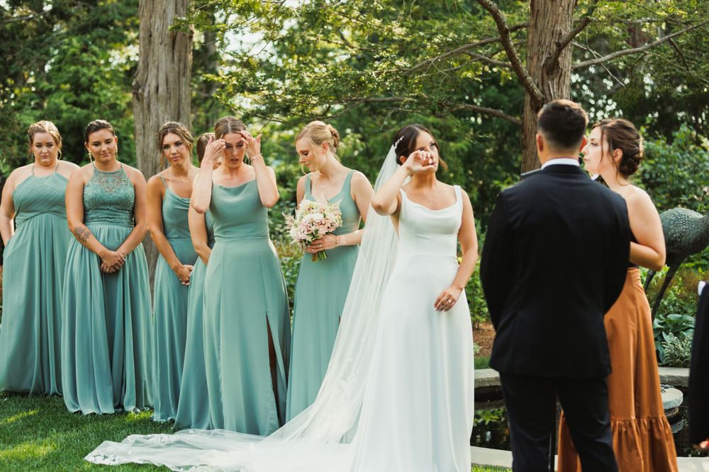 Bridesmaids in seafoam green dresses standing with bride in white gown at garden wedding.