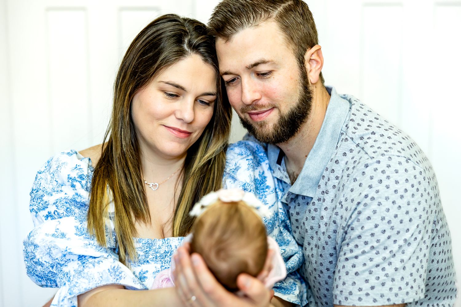 Parents hold up their new baby girl and gaze at her smiling during newborn photos in Colorado Springs.