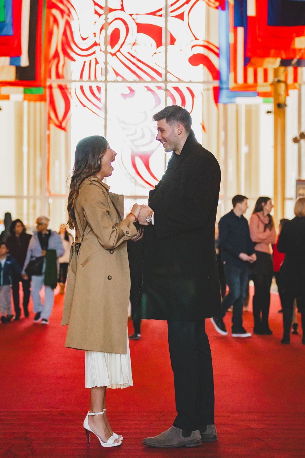 A couple shares an intimate moment on a red carpet surrounded by colorful art installations.