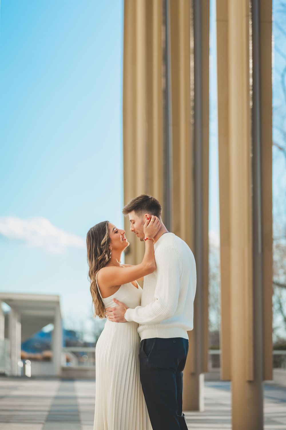 A romantic moment between a couple in white outfits against a backdrop of architectural columns.
