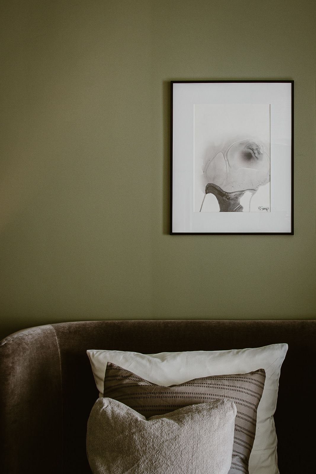 Headboard of a bed with pillows and green wall in the background