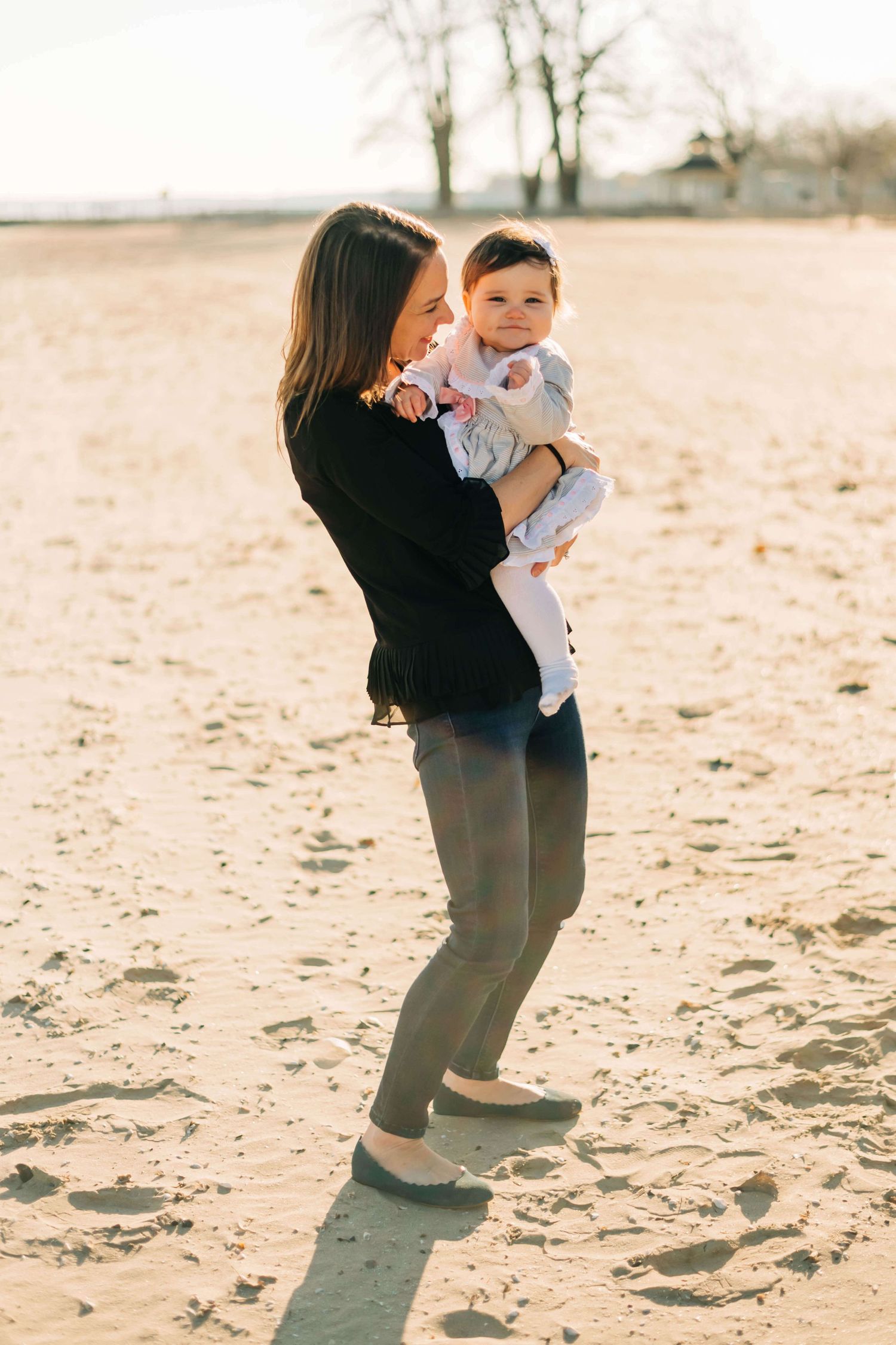 mother holding baby girl in the morning sun at a beach