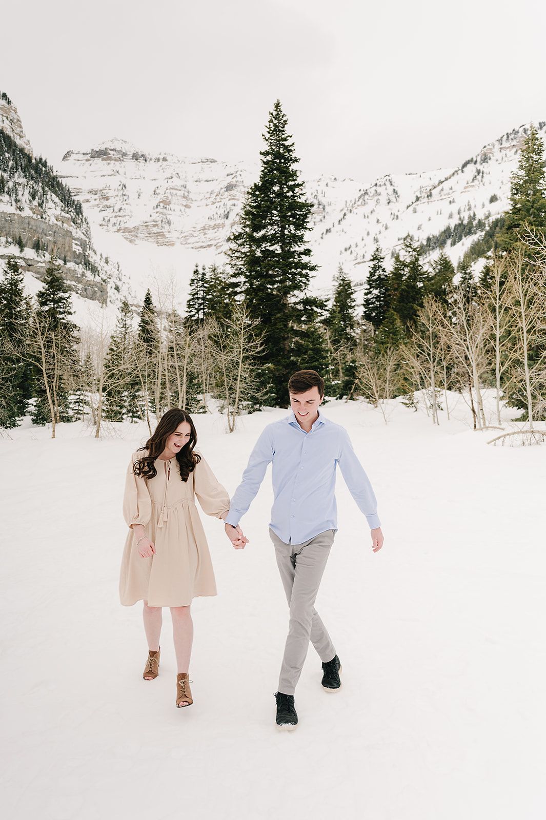 Winter engagement photos in snowy mountain landscape with evergreen trees.