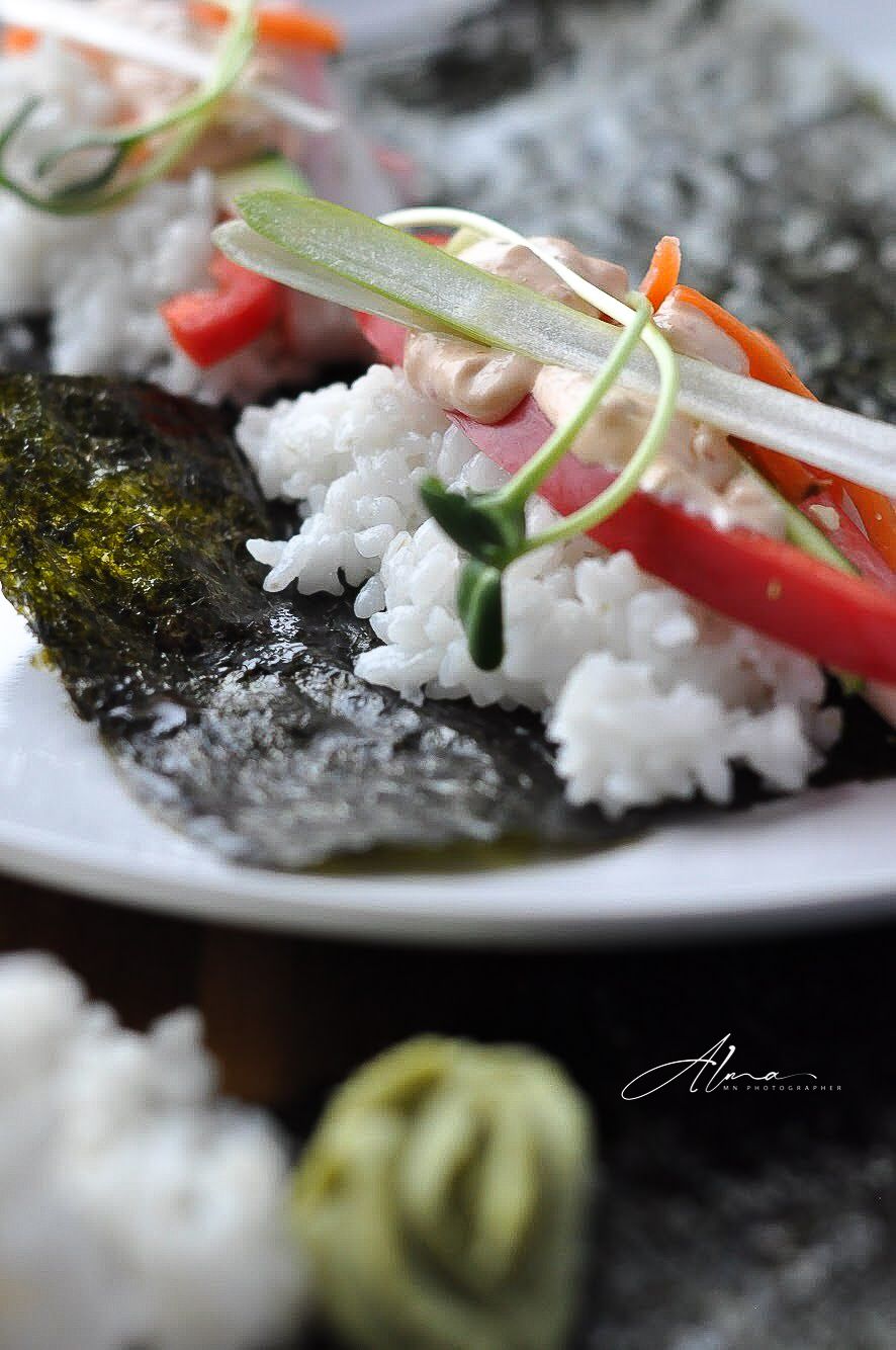 Detailed shot of sushi roll ingredients with fresh vegetables and rice on nori seaweed.