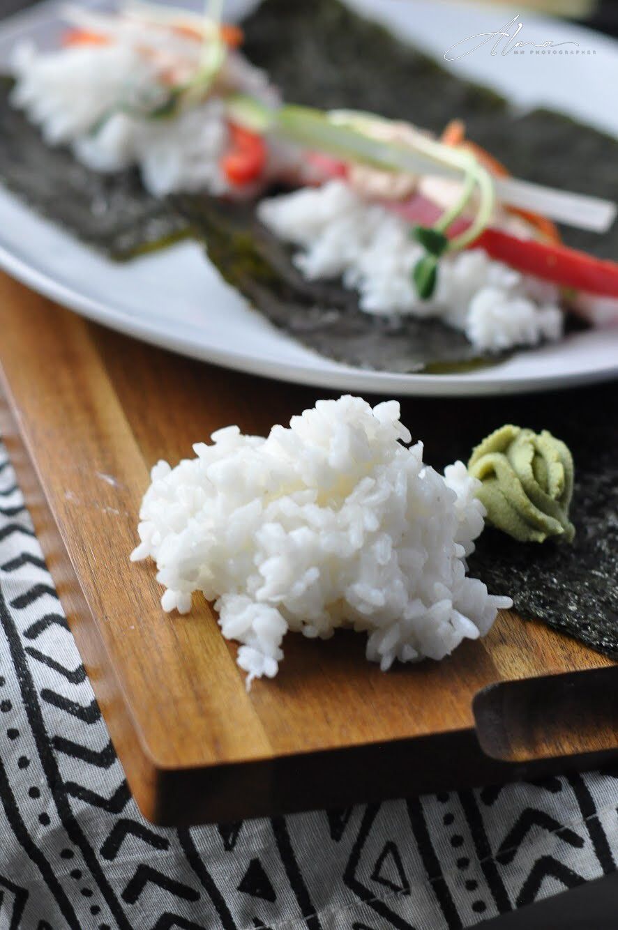 White sushi rice and wasabi on wooden board with geometric pattern cloth underneath.
