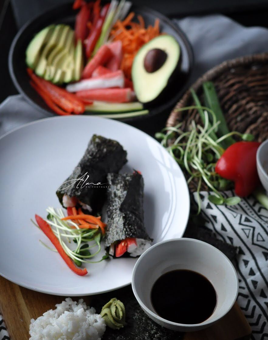 Deconstructed sushi ingredients with avocado, vegetables and nori served with soy sauce.