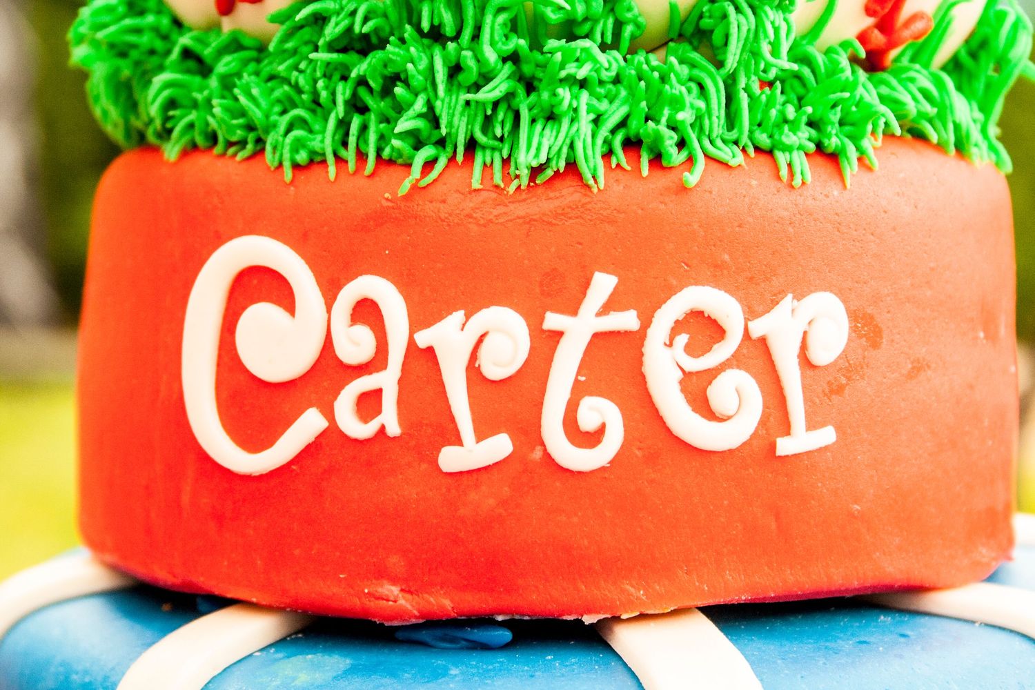 Detailed view of red fondant cake tier with Carter name in white lettering.
