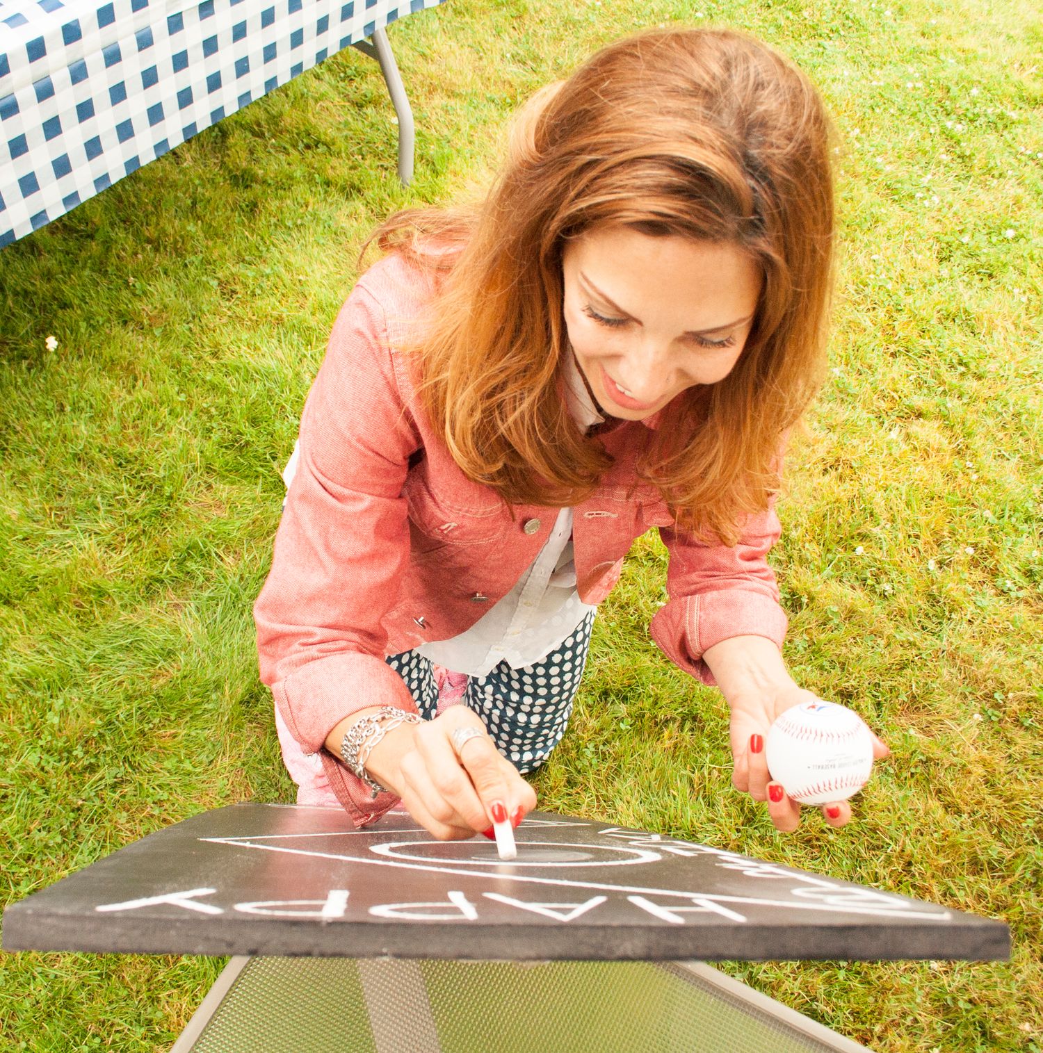 Person drawing on a chalkboard outdoors during party preparation.