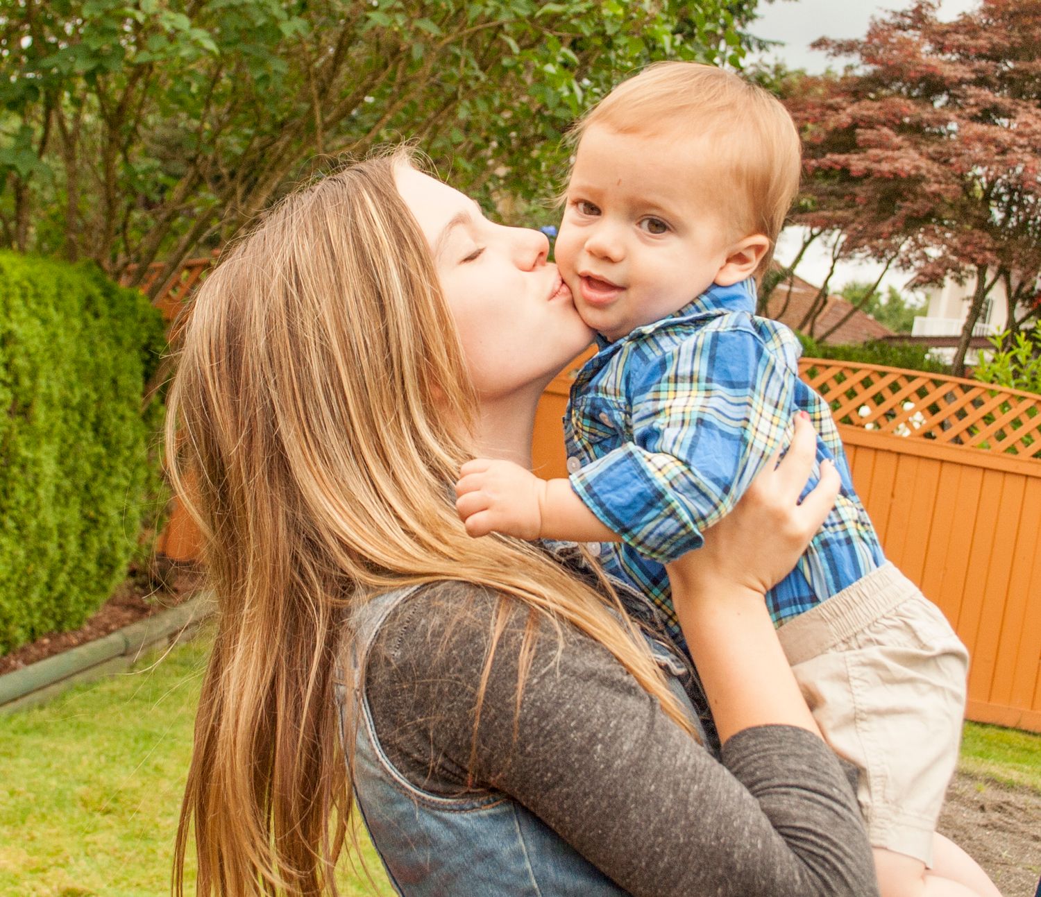 Tender moment captured outdoors with greenery in background.
