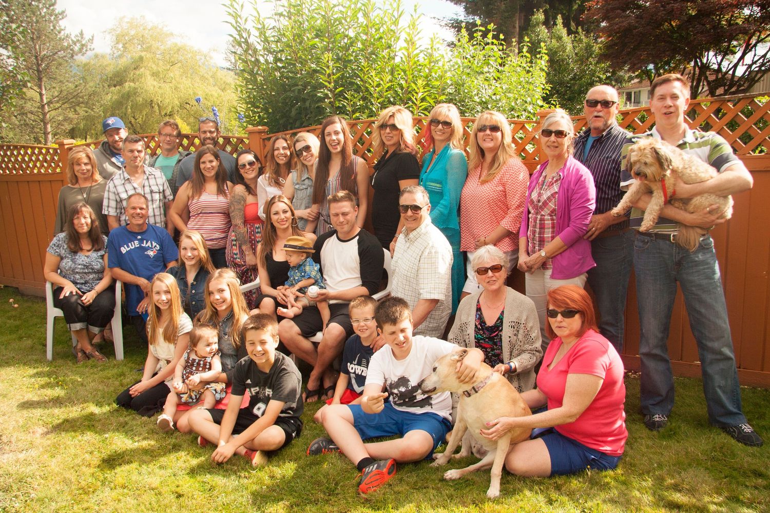 Large group gathering for outdoor family photo in backyard setting.