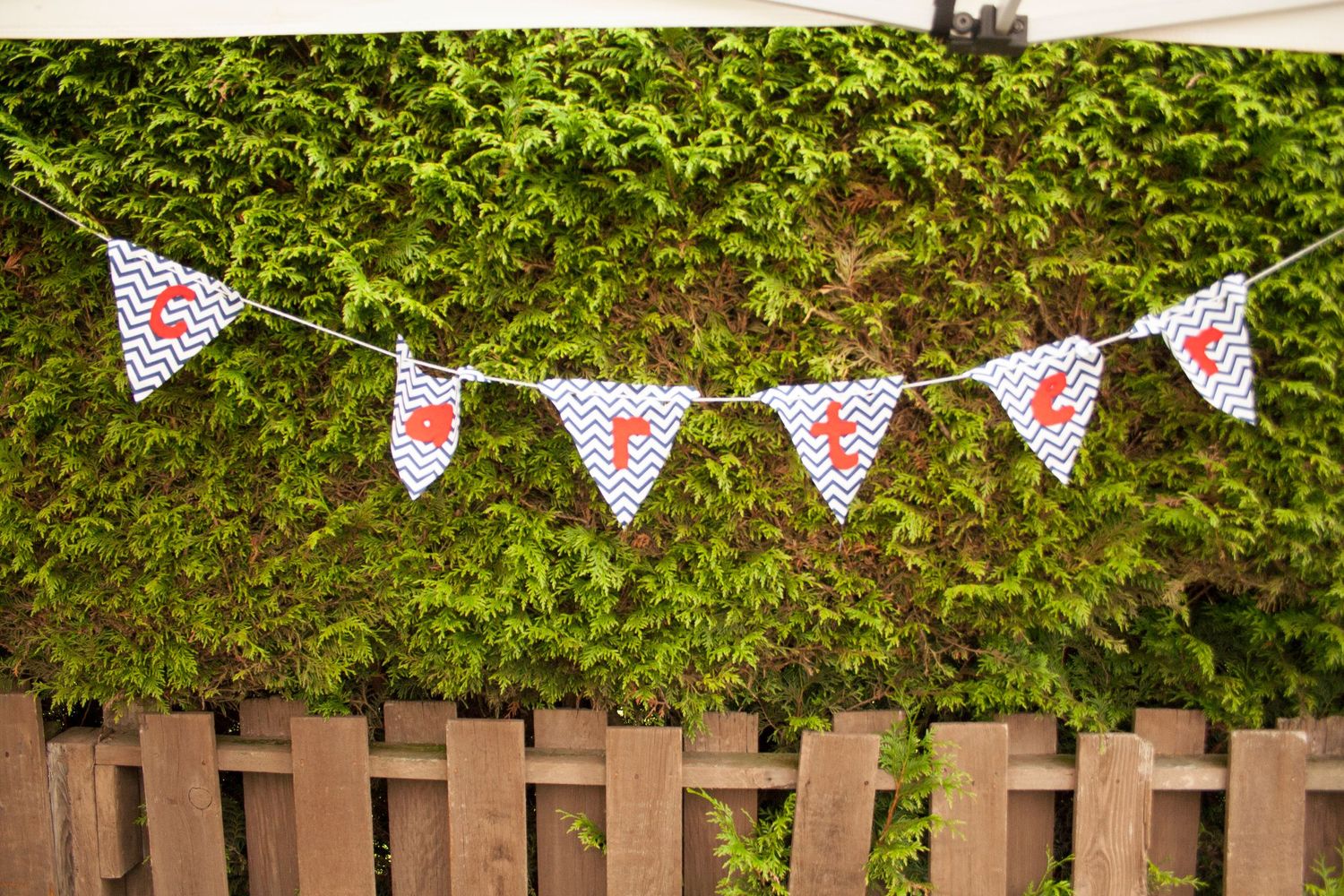 Decorative triangle banner bunting with hearts hanging on garden fence.