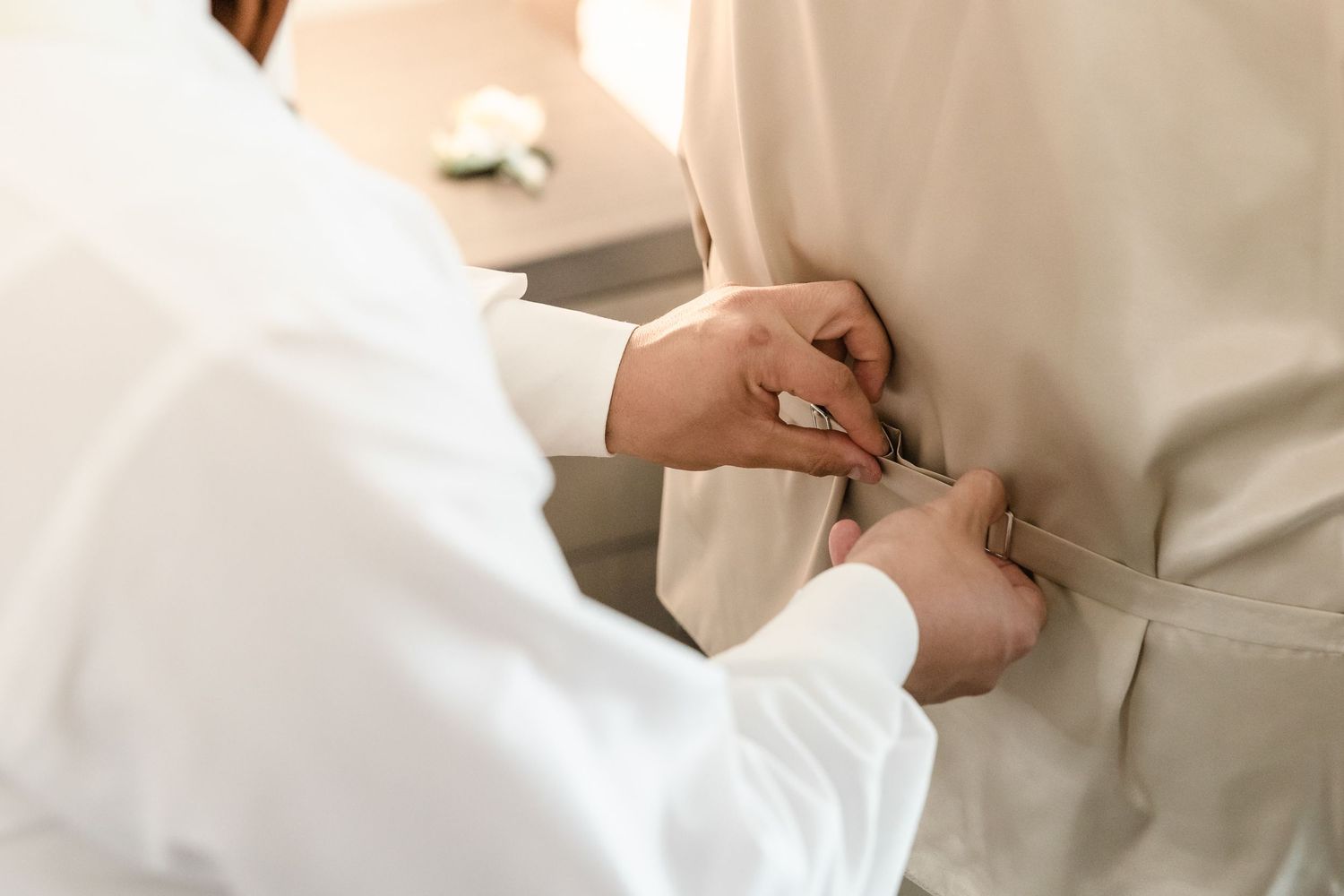 Someone adjusting a formal white suit jacket button in preparation for a special event.