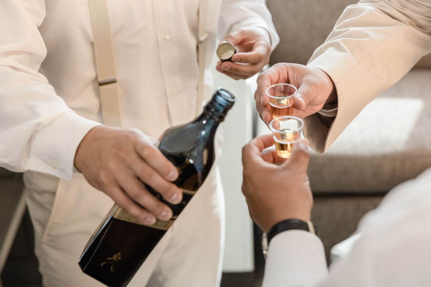 Hands holding wine glasses and bottle during celebratory toast.