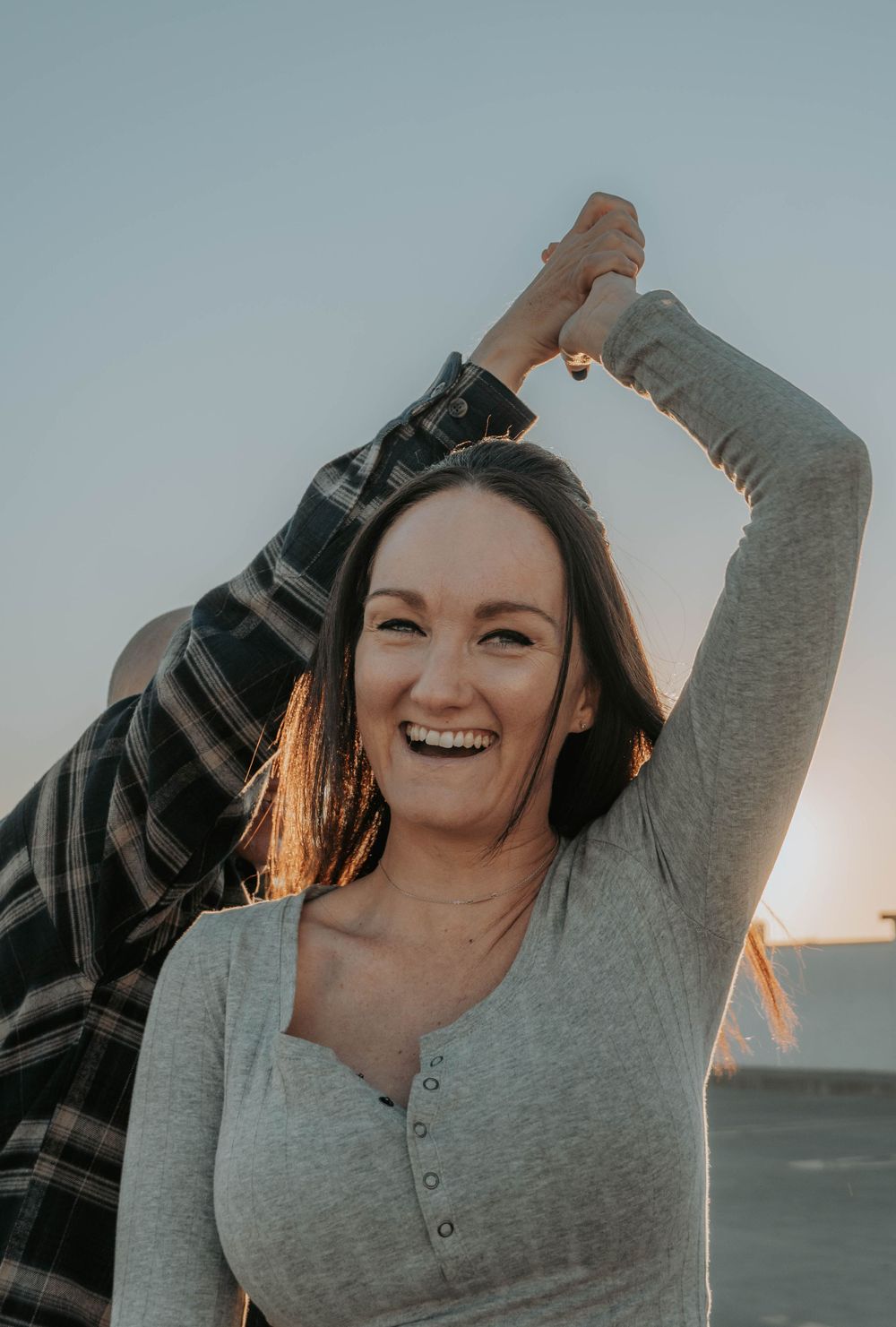 Woman in gray sweater enjoying a candid moment during sunset.