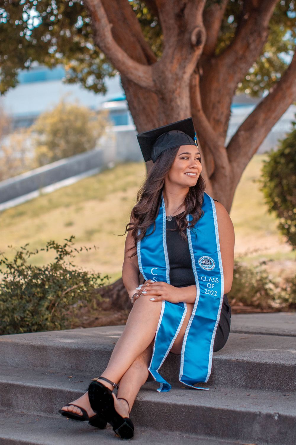 Graduation photo session showing an academic stole against a natural tree backdrop.