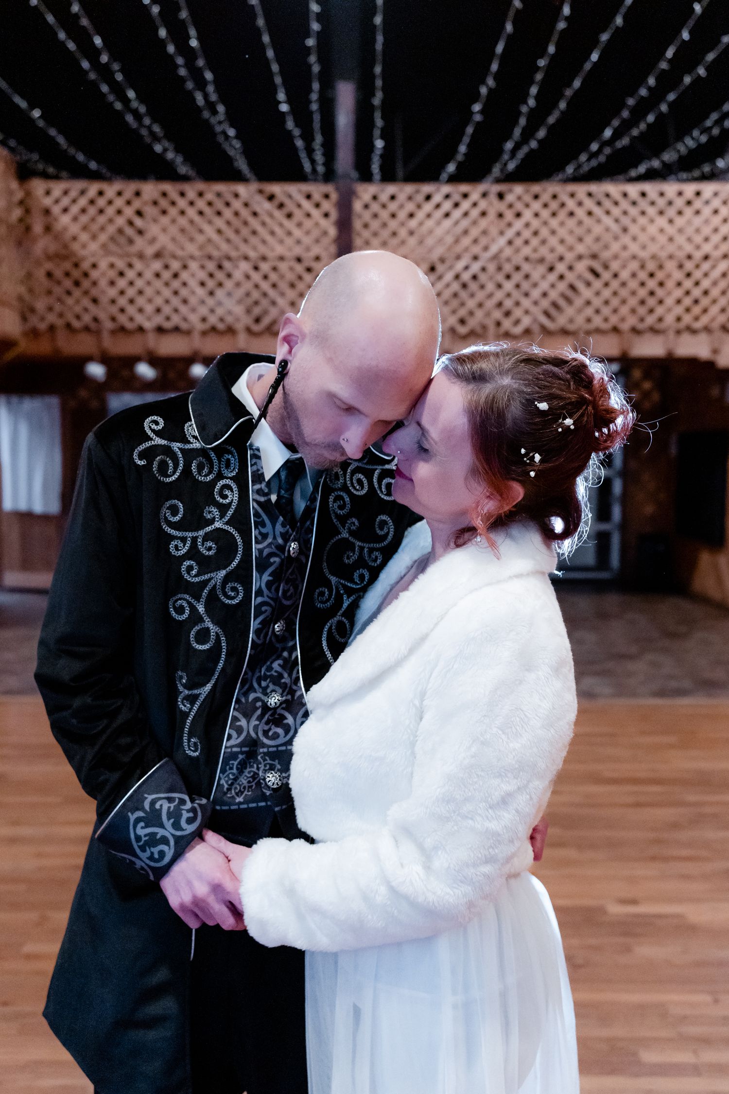 Bride and groom nuzzle in a barn hall