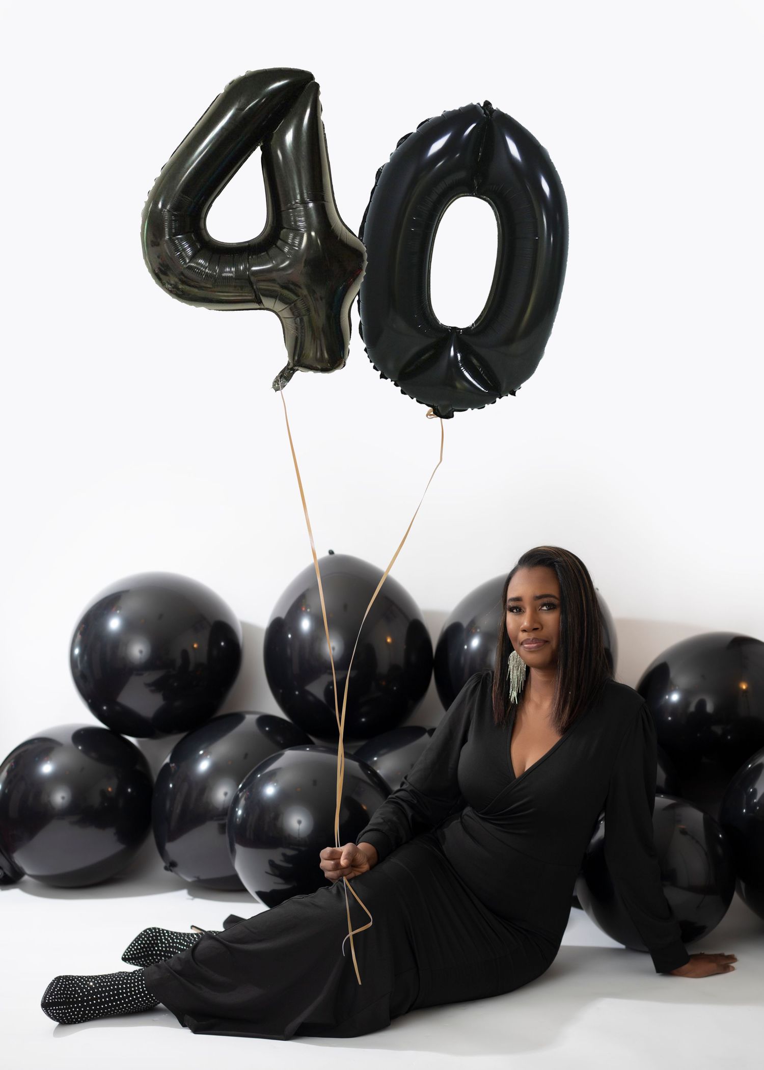 Stylish photoshoot with black balloons and number decorations creating a celebratory atmosphere.