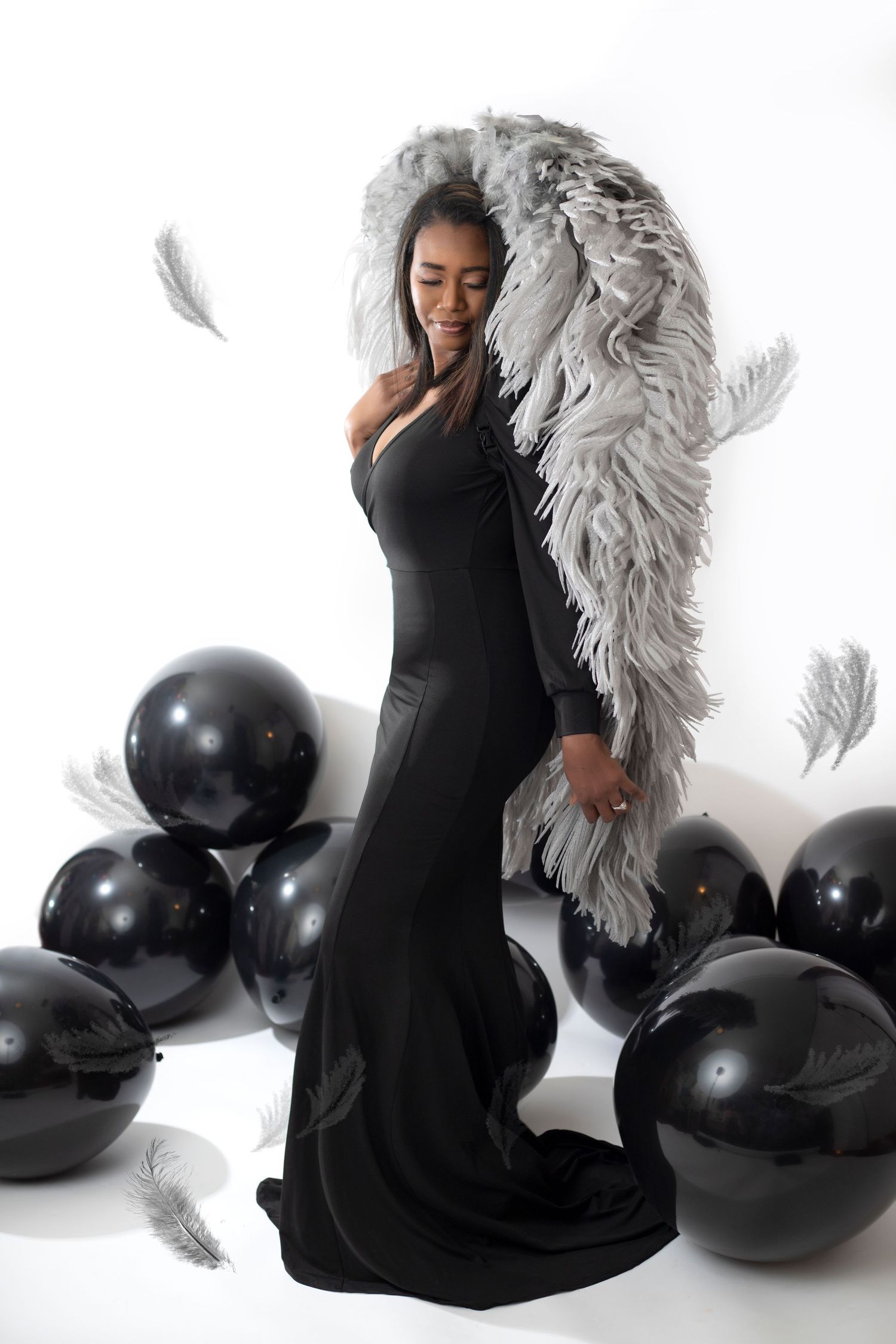 Elegant portrait session featuring white angel wings and black balloons against a white backdrop.