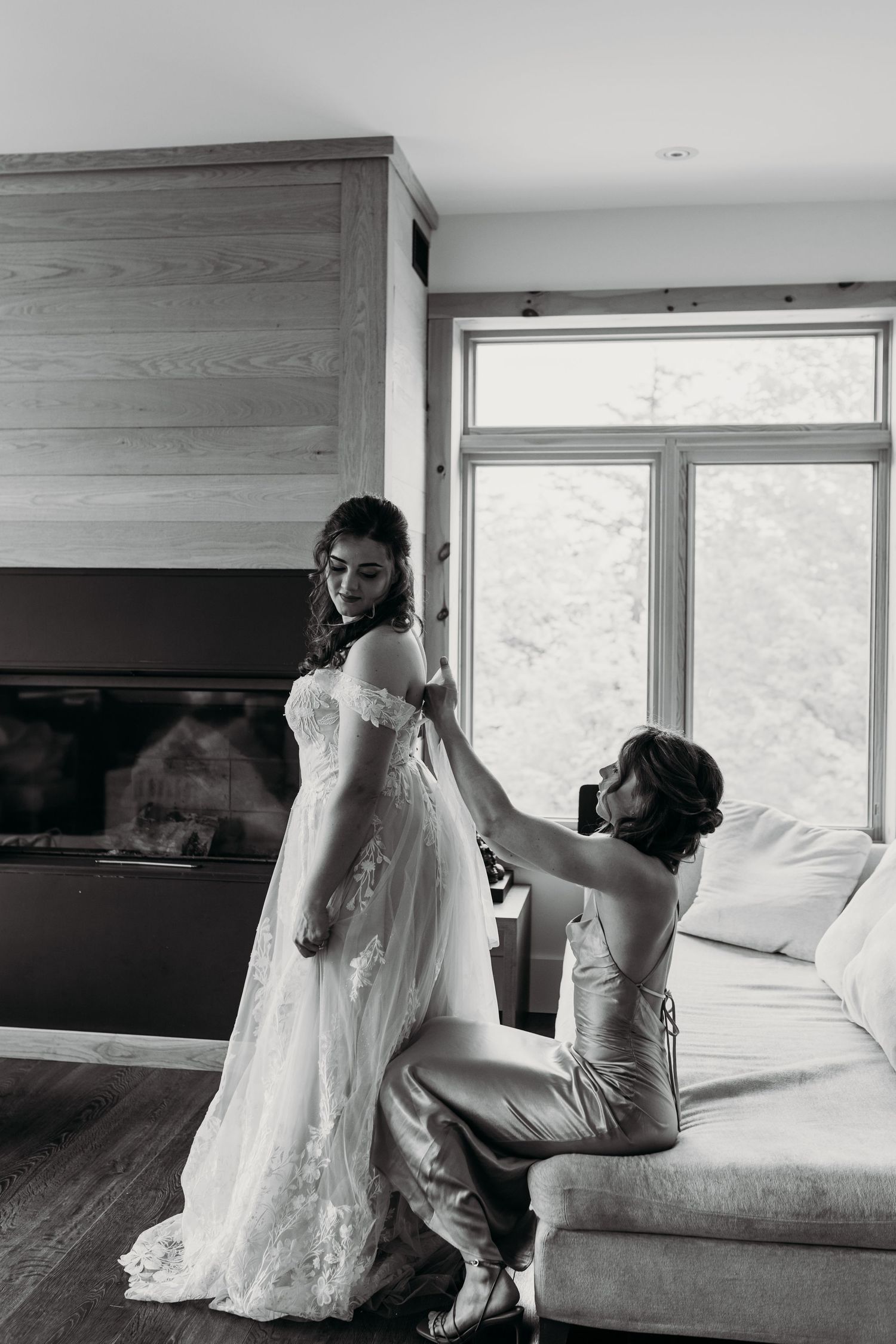 A black and white photograph of final dress preparations in a modern room with large windows.