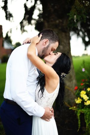 Intimate wedding couple sharing a romantic kiss in a garden setting.
