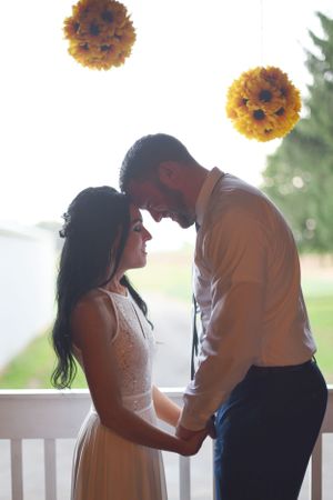Tender moment between couple with sunlit yellow pom pom decorations overhead.