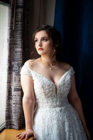 Classic bridal portrait by window showing detailed lace wedding dress.