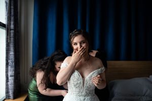 An emotional getting ready moment in a room with blue curtains on the wedding day.
