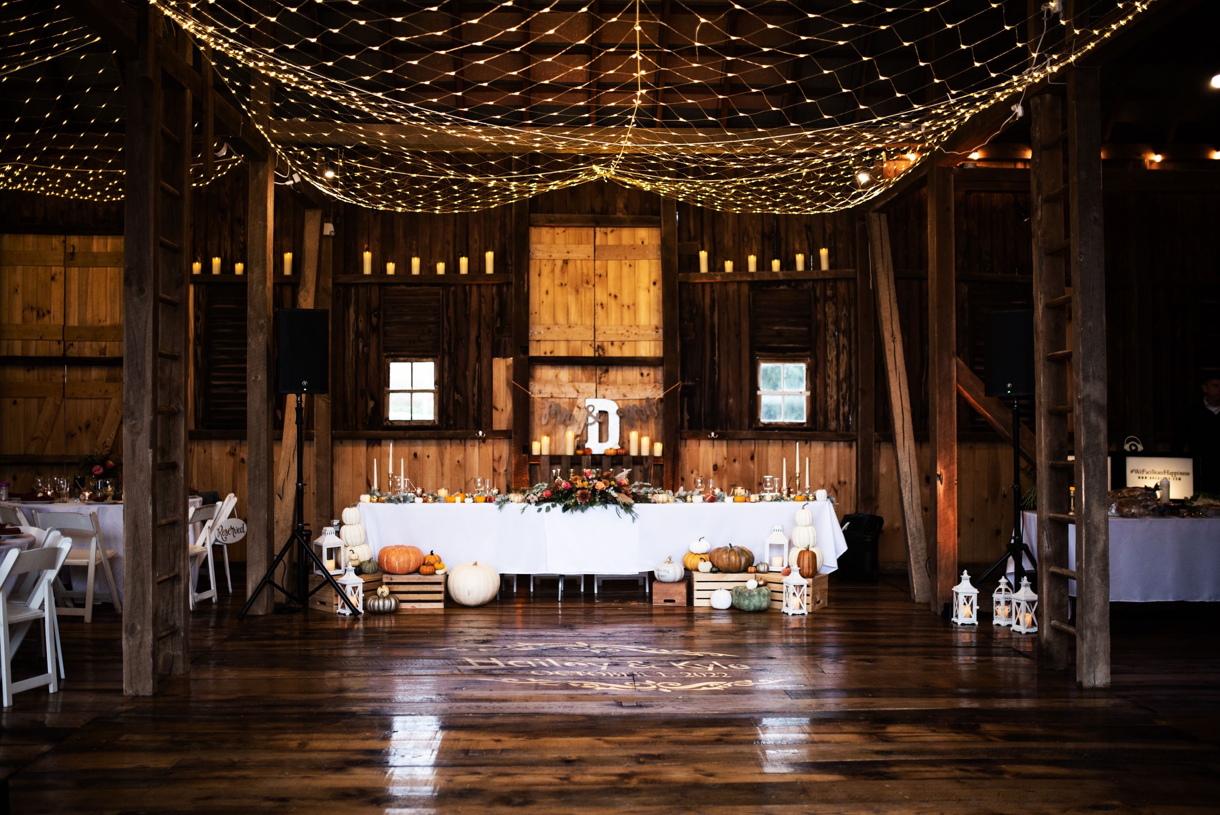 Rustic barn wedding reception venue decorated with twinkling lights and white table settings.