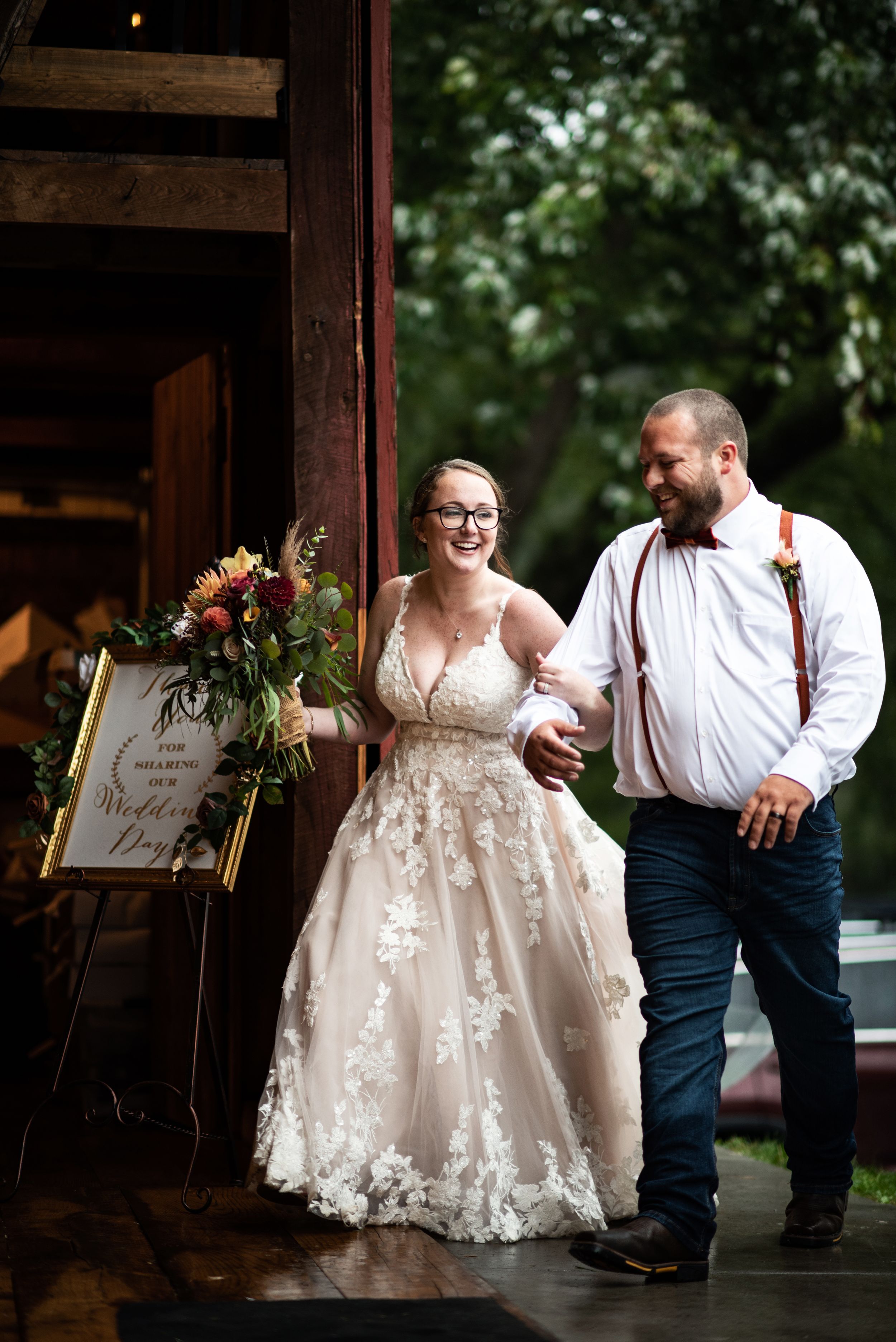 Newlyweds share a joyful moment exiting their rustic barn wedding venue.