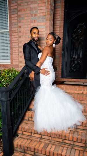 Elegant wedding couple pose on brick stairs in formal attire.