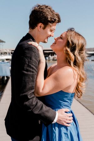 Romantic couple embracing and laughing together on waterfront dock.