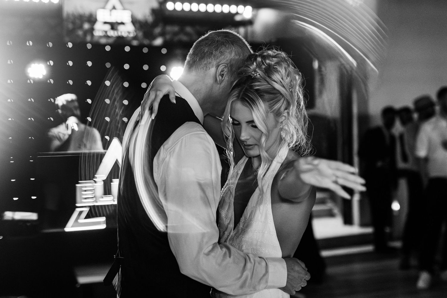 A romantic black and white wedding photo shows a bride dancing with her father at dance floor