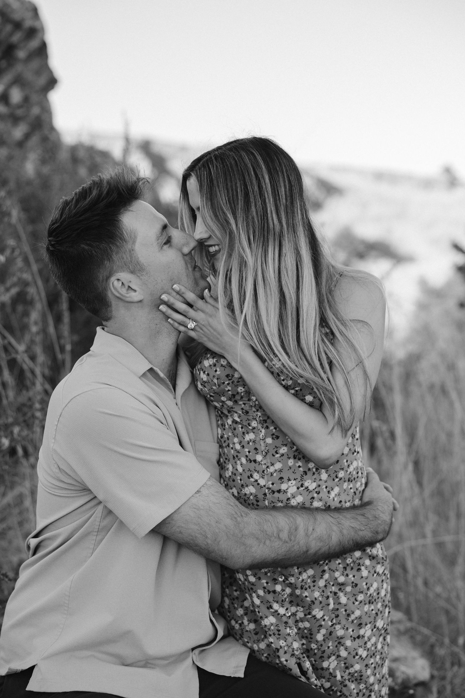 Black and white photo of couple sharing intimate moment in outdoor setting.