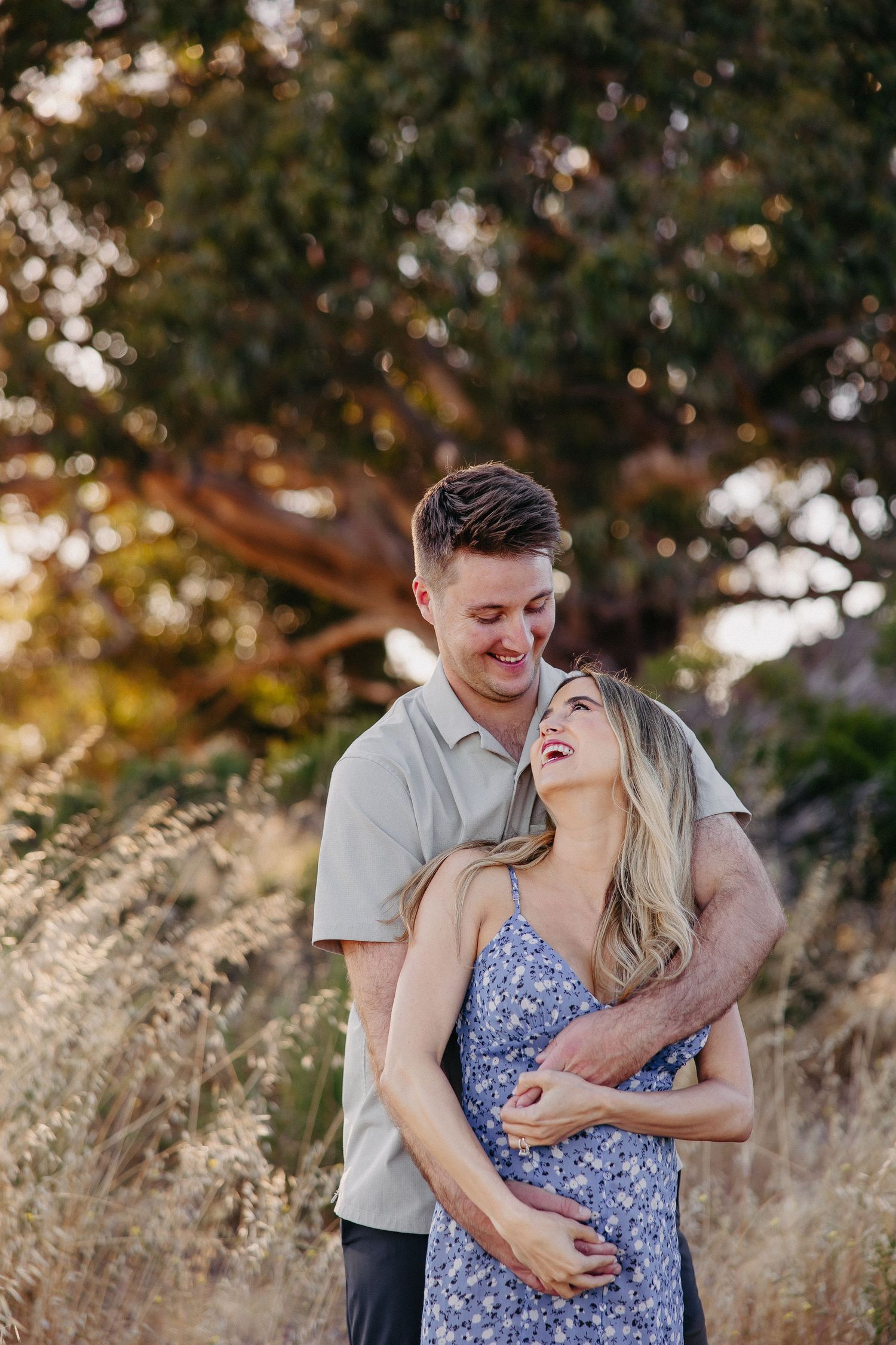 Happy couple laughing together in warm evening light surrounded by nature.