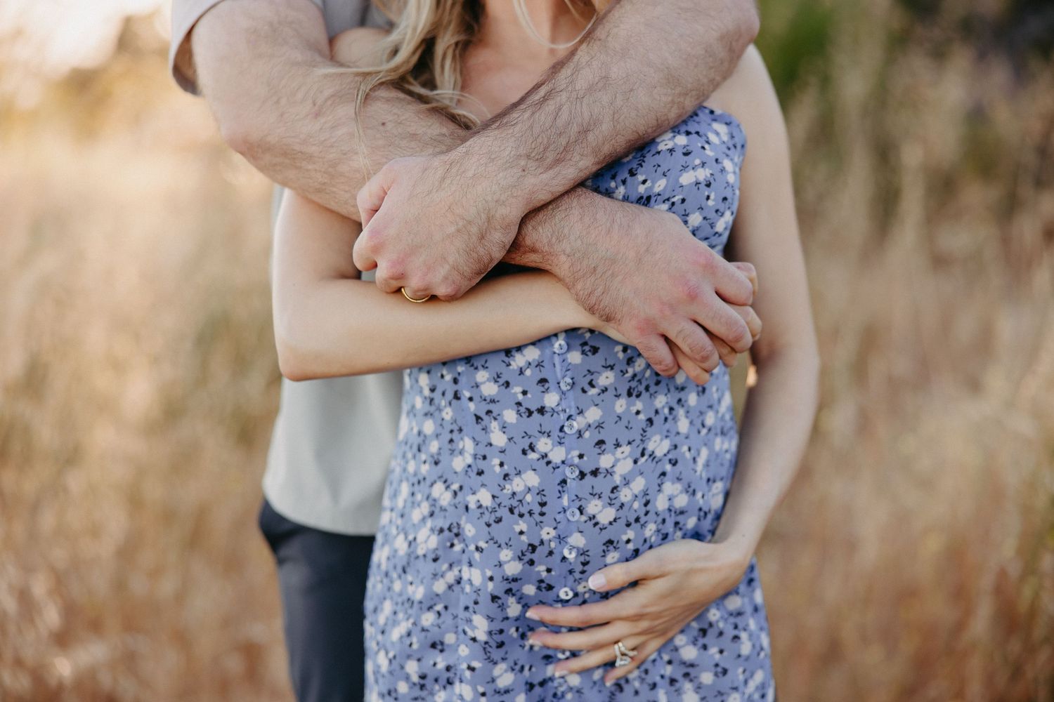 Close up of couple's embrace in floral dress against natural backdrop.